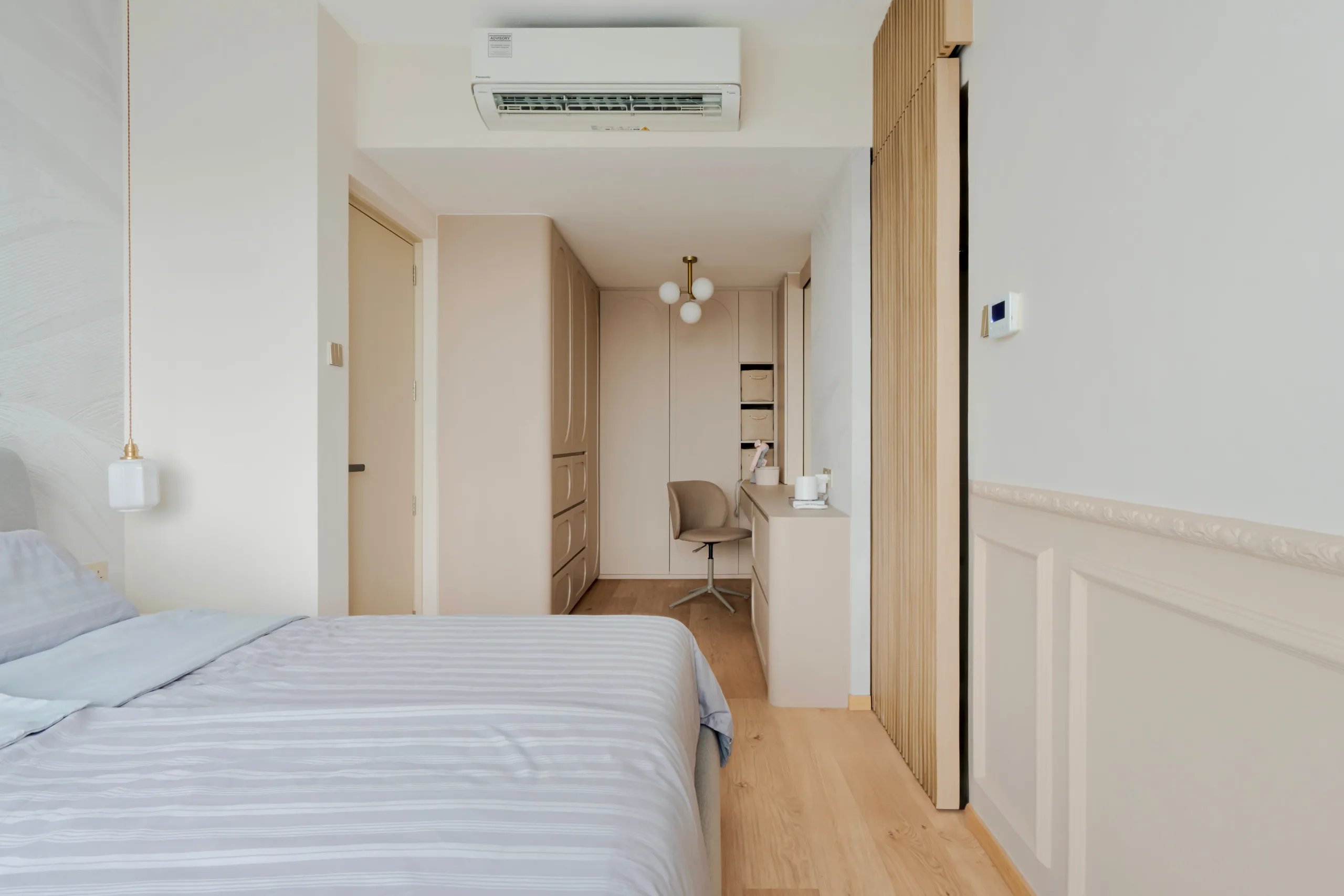 Master bedroom at Watercolours EC with wainscoting, oak flooring and a built-in wardrobe running into a dressing desk