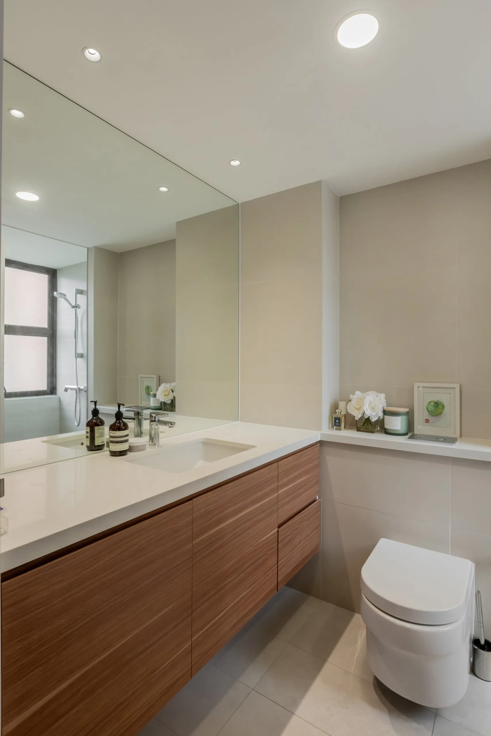 Long wood-toned floating vanity with a white top and undermount basin below a wide wall mirror